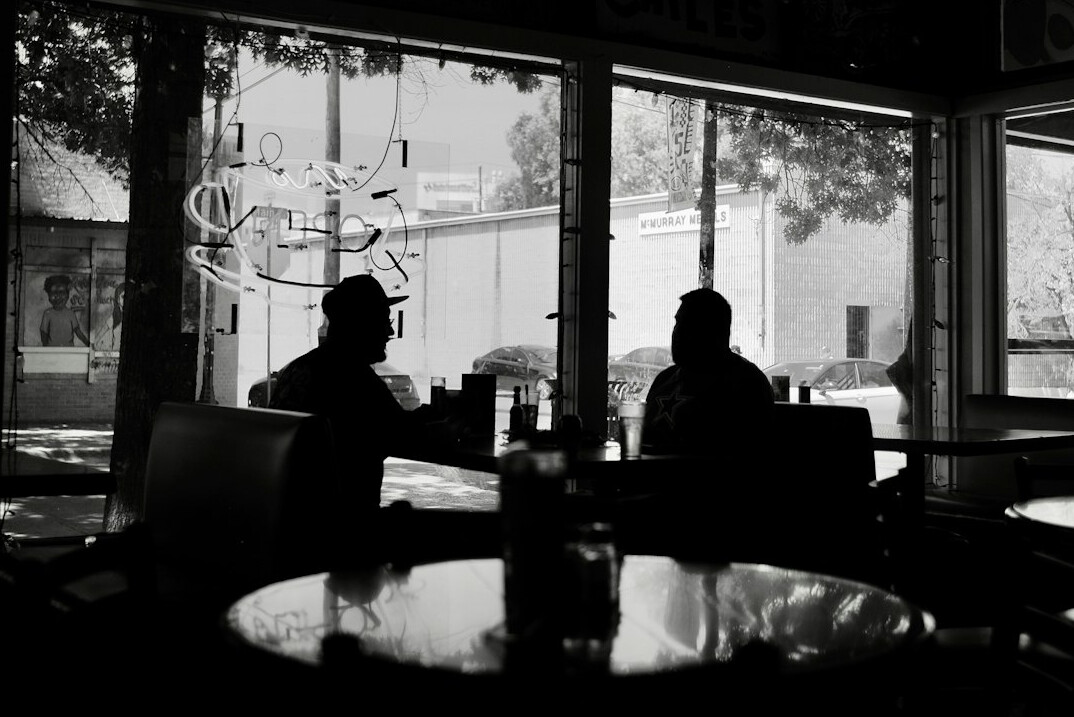 Two friends chatting over coffee at a small neighborhood cafe table