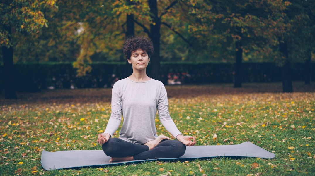 person meditating in park