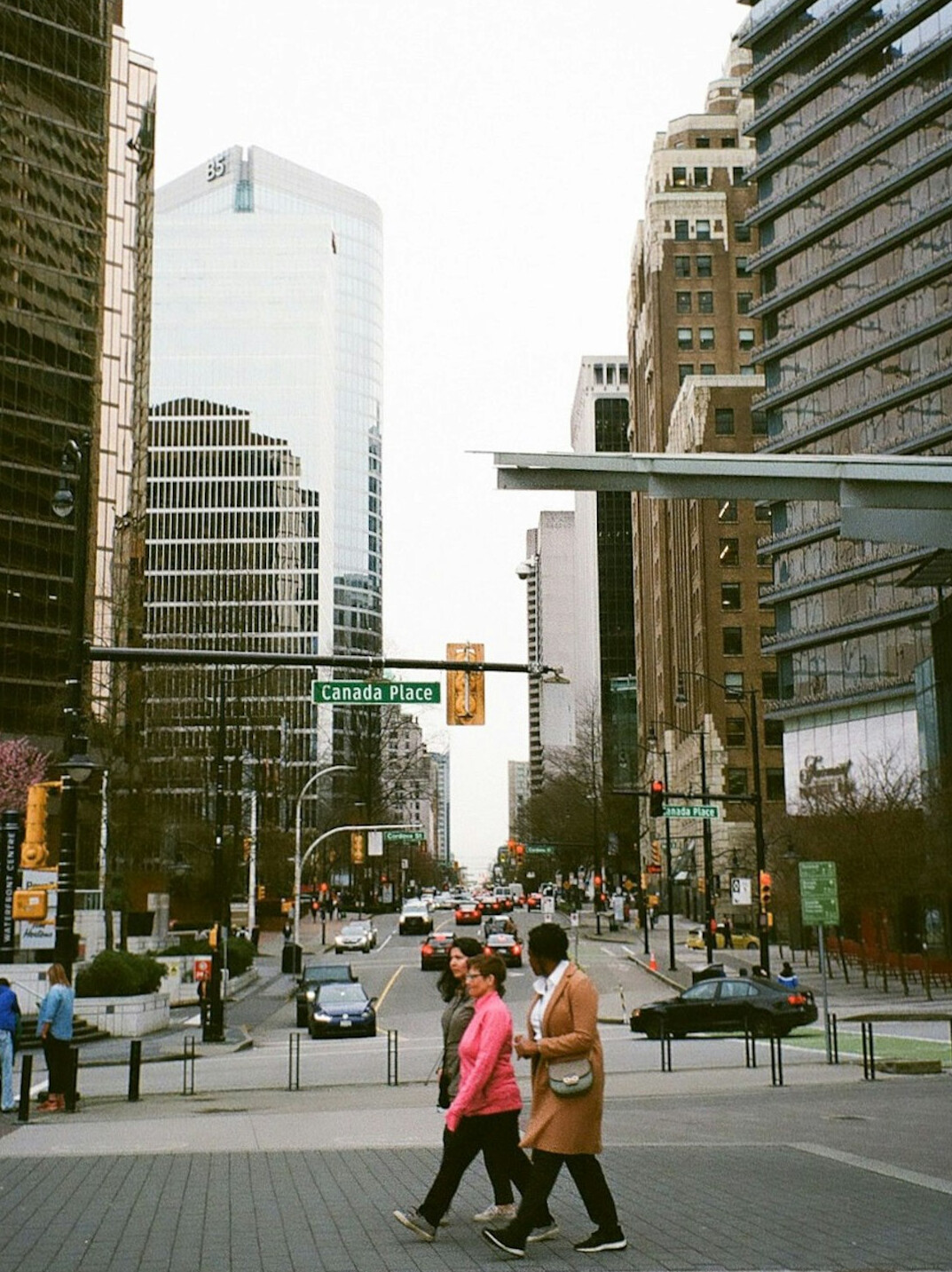 People walking across a busy downtown Canadian city crosswalk in the morning