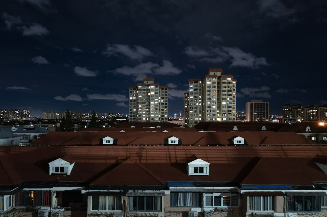 City skyline with lit windows at dusk seen from a residential rooftop